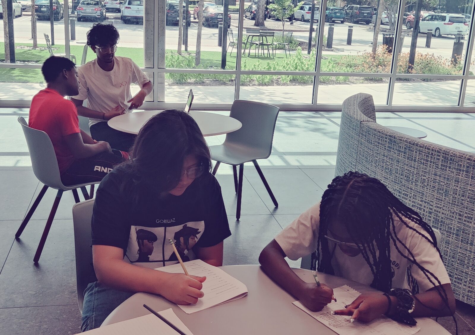 Students writing in notebooks at study tables in the library.