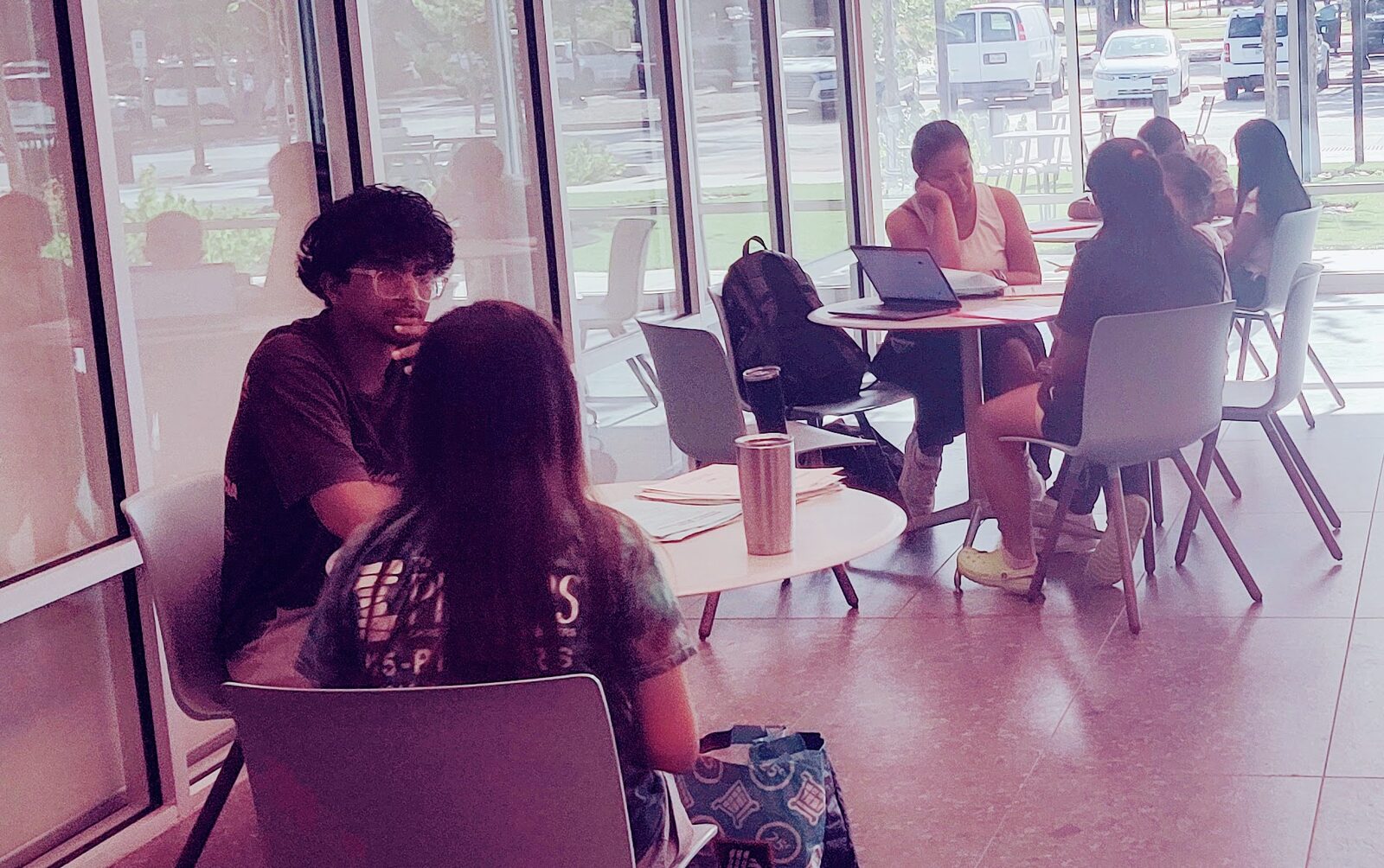 A tutor and a student talking through a question at a library table.