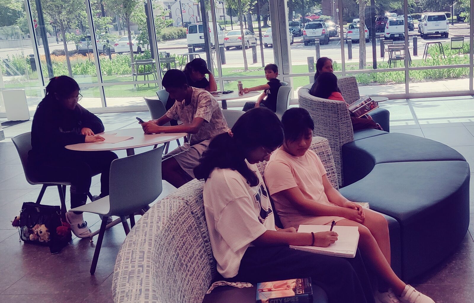Students sitting together on library couches, taking notes side by side.